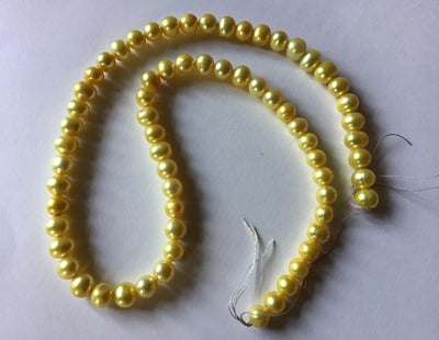 Perler, En hel streng ÆGTE FERSKVANDSPERLER i en yndig gul farve. Perlerne er 6-7 mm og strengen er 