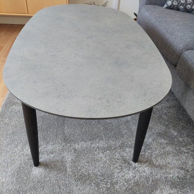 Sofabord, Katrine, laminat, b: 68 l: 128 h: 50, Ovalt bord med granitgrå bordplade og sorte bordben.