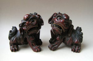A pair of well-carved Chinese lacquered wooden Buddhist lions with inlaid eye...