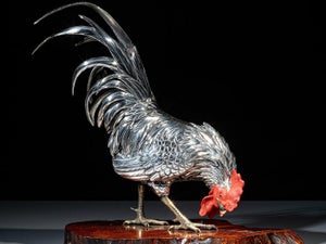 A superb and realistic silvered bronze okimono of a rooster standing on a nat...